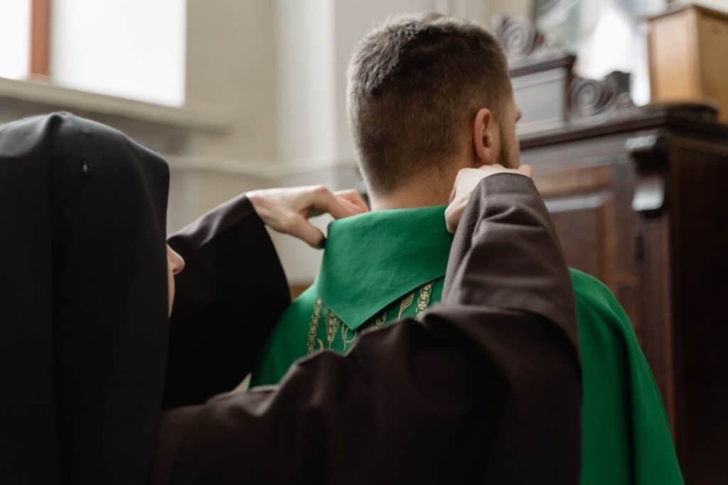 a priest getting help in fixing his stole