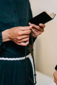 person holding a bible and a rosary