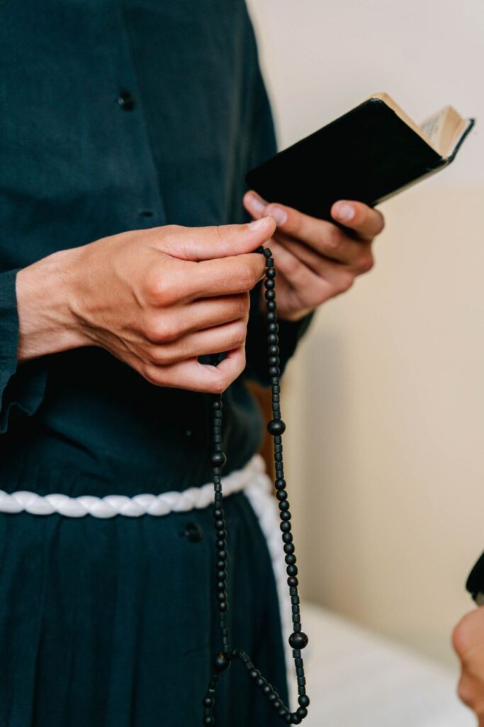 person holding a bible and a rosary